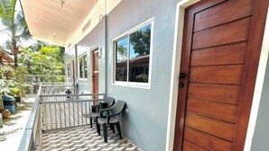 A covered outdoor area with a wooden door, a window, and a small seating area with chairs. - Cozy Studio Type unit w/ TV, Wifi, hotshower & ref (Cotabato)