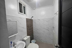 A bathroom with a toilet, sink, and shower. - Cozy Studio Type unit w/ TV, Wifi, hotshower & ref (Cotabato)