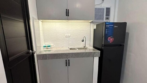 A compact kitchen with a sink, a refrigerator, and cabinets. - Cozy Studio Type unit w/ TV, Wifi, hotshower & ref (Cotabato)