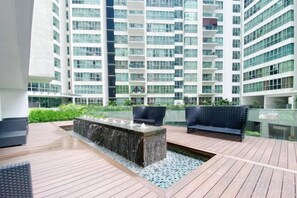 A rooftop terrace with a fire feature, seating, and a view of high-rise buildings. - Homestay near to PWTC @ BY AWESOMESTAY (Kuala Lumpur)