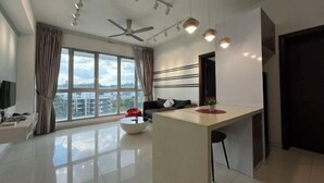 A modern living room with a large window, a ceiling fan, recessed lighting, a sofa, a coffee table, and a TV. - Homestay near to PWTC @ BY AWESOMESTAY (Kuala Lumpur)