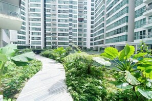A pathway surrounded by lush greenery in a modern building complex. - Homestay near to PWTC @ BY AWESOMESTAY (Kuala Lumpur)