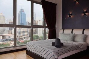 A bedroom with a large window, a bed with striped bedding, and a city view.