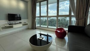 A modern living room with a large window, a flat-screen TV, a coffee table, and a red accent chair. - Homestay near to PWTC @ BY AWESOMESTAY (Kuala Lumpur)