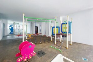 A children's play area with a swing set, climbing structures, and a colorful octopus toy. - Homestay near to PWTC @ BY AWESOMESTAY (Kuala Lumpur)