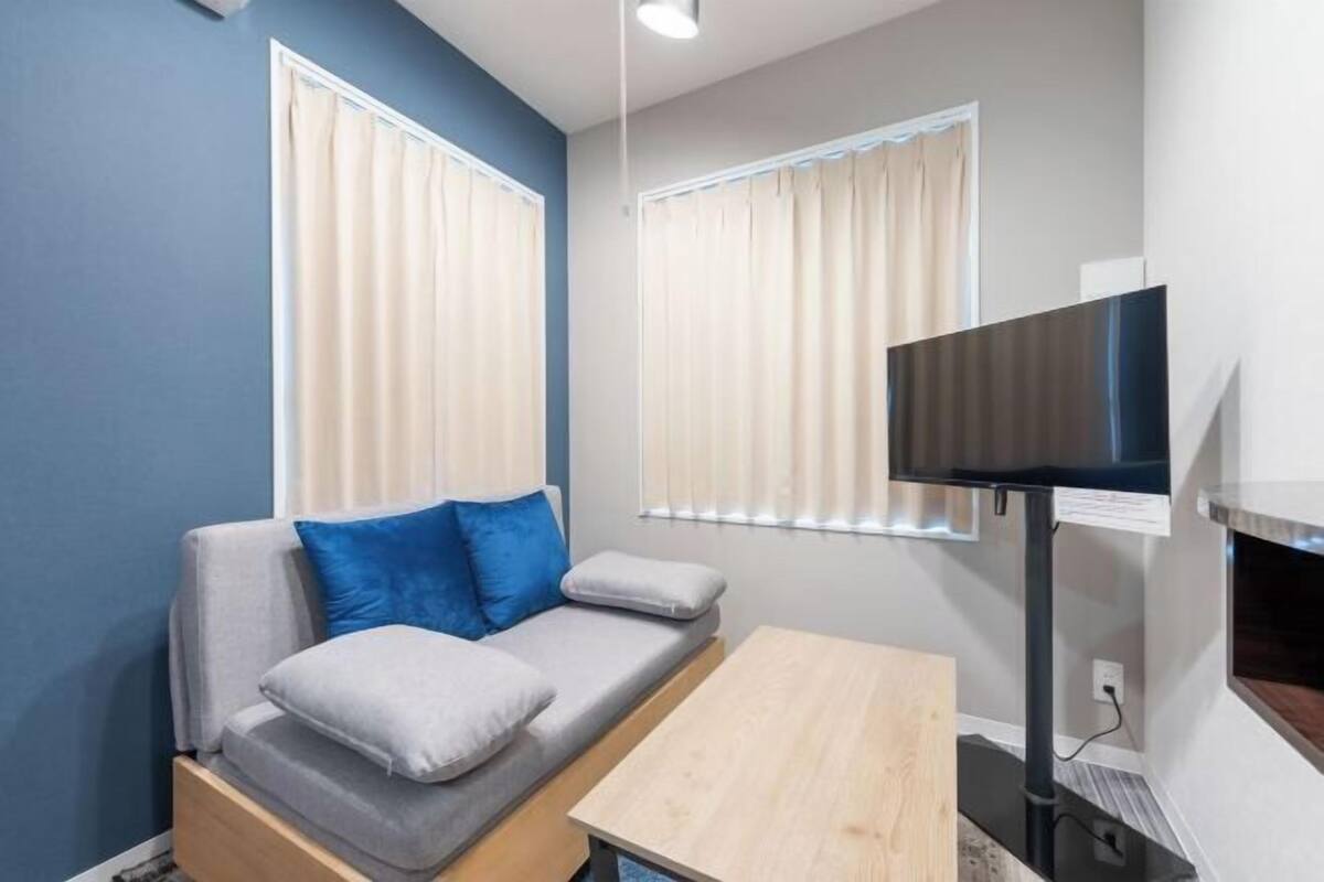 Una habitación pequeña con sofá, televisión y mesa de madera.