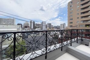 A balcony with a wrought iron railing overlooking a cityscape with multiple buildings.
