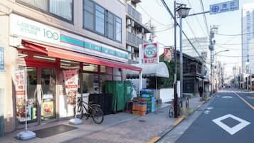 A Lawson store with a red awning, a bicycle parked outside, and a street with a speed limit sign.
