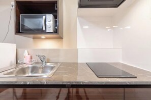 A kitchen with a built-in microwave, a stainless steel sink, and a black countertop. - The Sanctus Ebisu (Tokyo)
