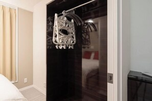 A hotel room with a bed, a door with a towel rack, and a mirror reflecting part of the room.