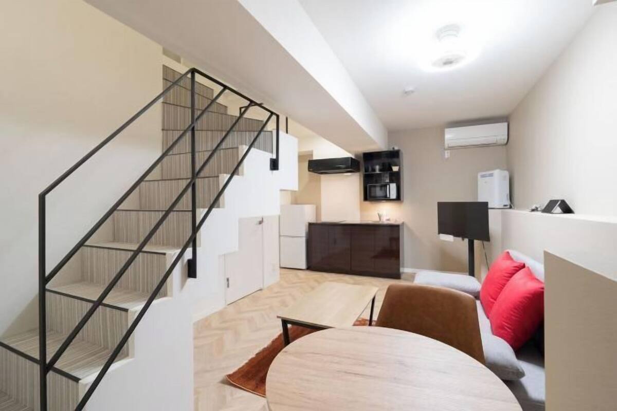 Un interior moderno con una escalera, una zona de comedor y una cocina.