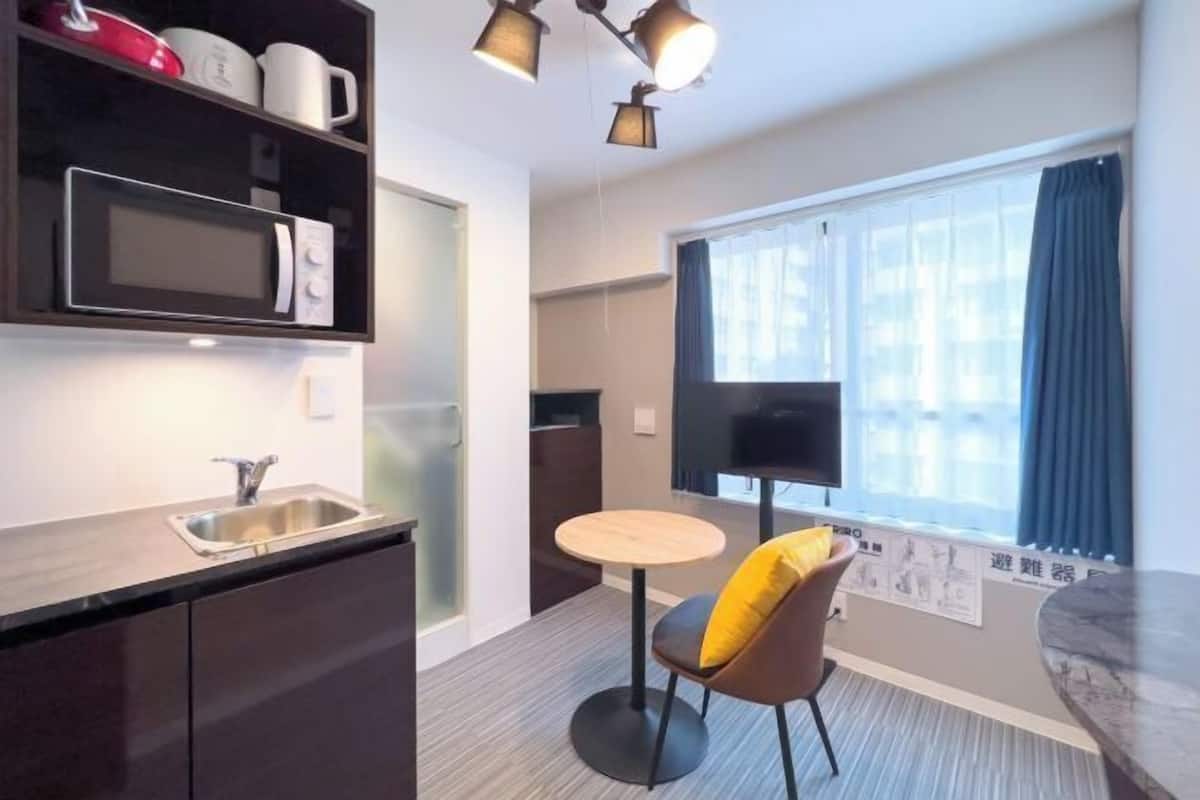 Una cocina compacta con microondas, pileta y un pequeño comedor con una silla y mesa.
