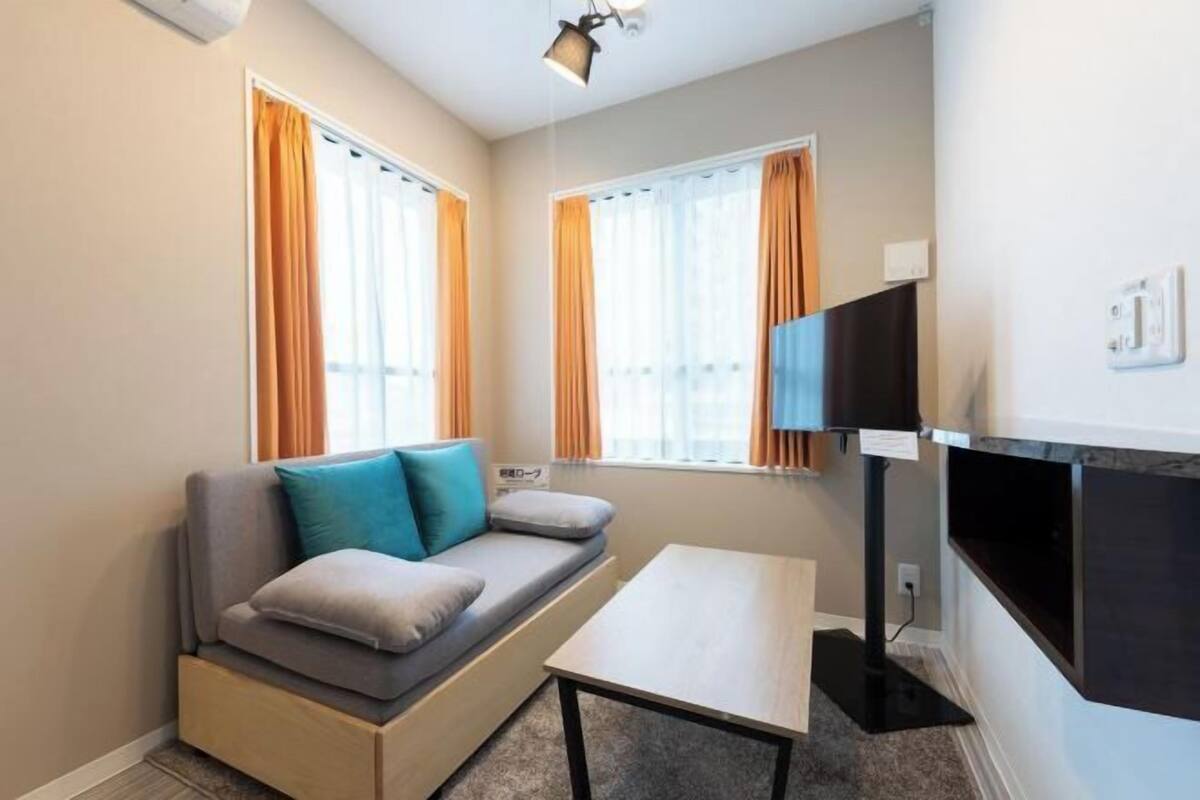 Una habitación compacta con sofá, una mesita y un televisor montado en la pared.