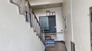 Un couloir avec un escalier, un téléviseur fixé au mur et une table avec des bouteilles d’eau.