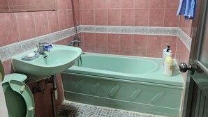 Une salle de bain avec un lavabo vert, une baignoire et des toilettes.