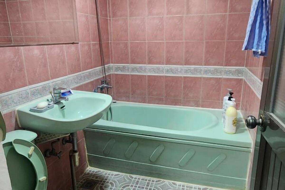 Un baño con un lavamanos verde, una bañera y un inodoro.