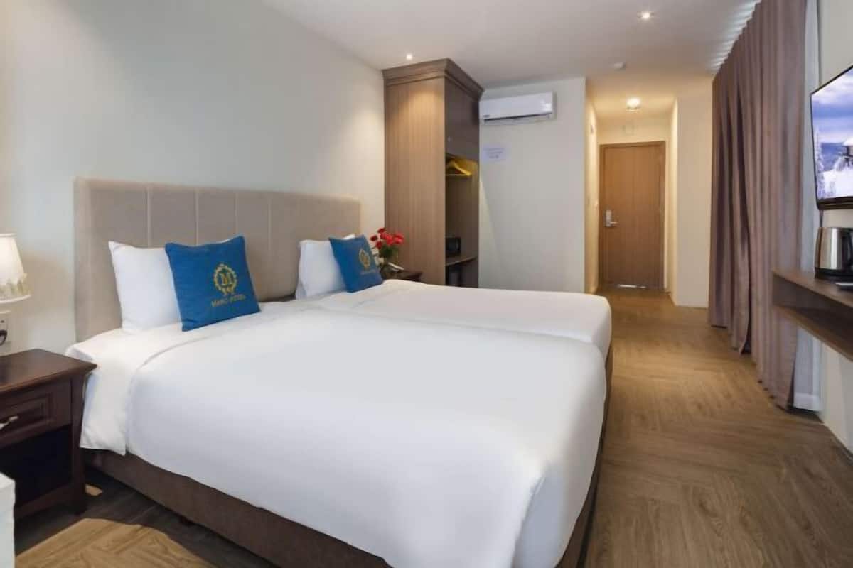 A hotel room with a large bed, a nightstand, a dresser, and a television.