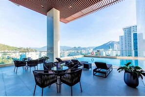 Une terrasse sur le toit avec une piscine, un espace salon et une vue sur la ville et les montagnes.