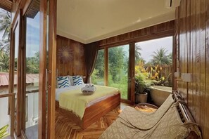 A bedroom with a bed, a window, and a view of the outdoors. - Baan Proud Proud (Khanom)