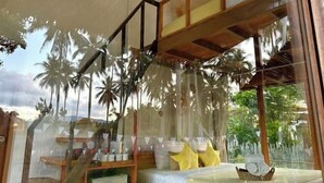 A room with a large window, wooden staircase, and a view of palm trees.