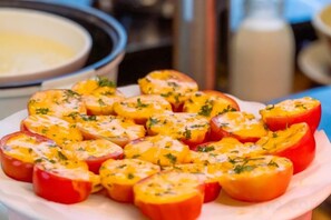 A plate of halved tomatoes topped with cheese and herbs.