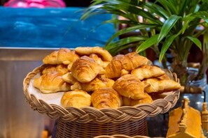 Una cesta con varios pasteles, incluyendo croissants y otras delicias horneadas.