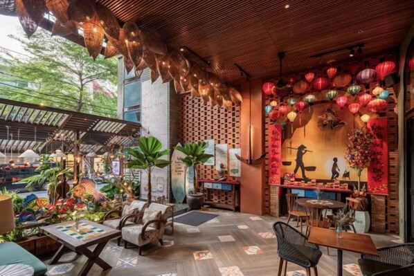 An indoor dining area with tables and chairs, a wooden ceiling, and decorative lanterns.