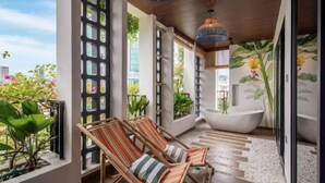 A balcony with wicker chairs, a bathtub, and a view of the city. - Tropical Dorm Hostel Da Nang by Haviland (Da Nang)