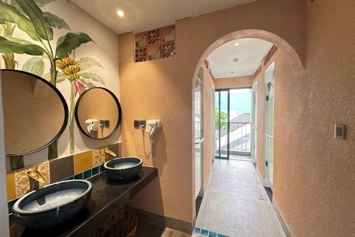 Casa de banho com duas pias, um espelho grande e uma planta.