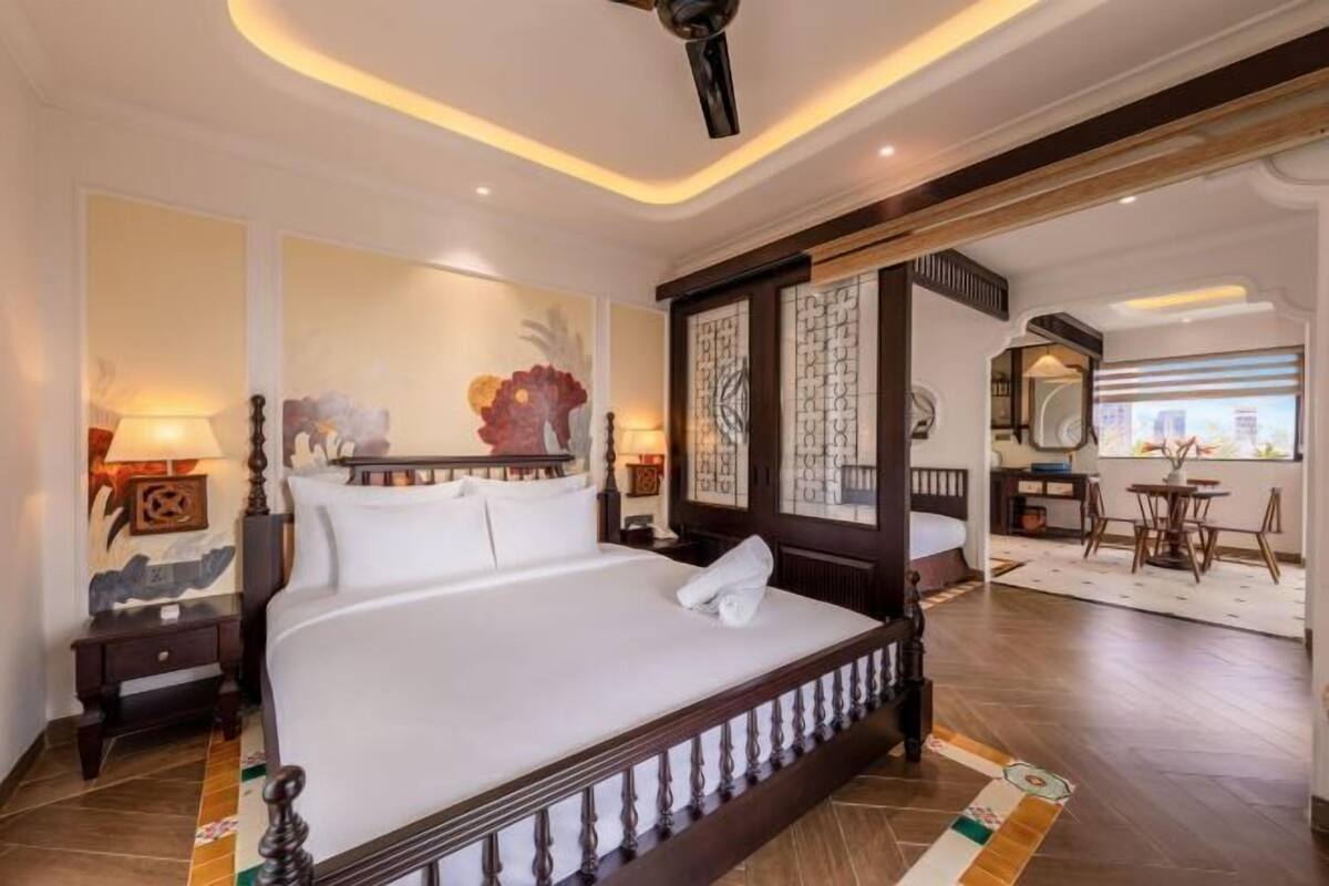Um quarto espaçoso com uma cama grande, um ventilador de teto e vista para a cidade através de uma janela.