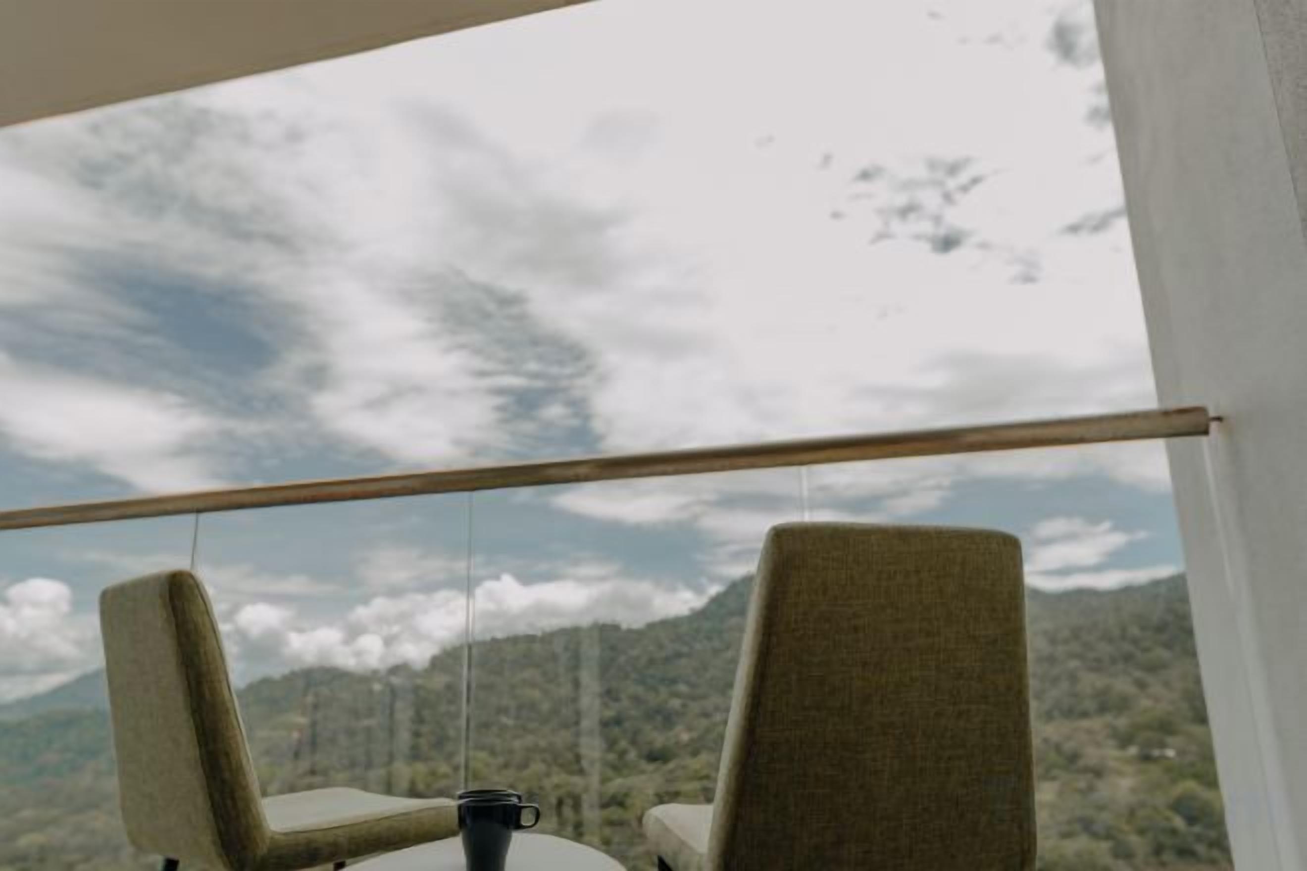 Un balcón con dos sillas y una mesa, con vistas a un paisaje montañoso.