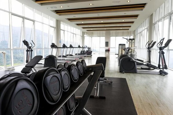 Une salle de sport équipée de tapis de course, de vélos elliptiques et d’appareils de musculation.