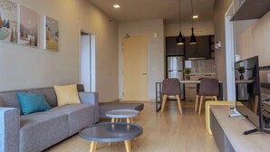 A modern living room with a sofa, two round tables, and a kitchen area with a dining table and chairs. - Windmill Upon Hills By Rapi (Genting Highlands)