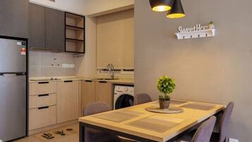 A compact kitchen with modern appliances, a dining table with chairs, and a small potted plant.