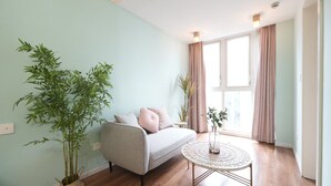 Ein Wohnzimmer mit einer Couch, einem runden Couchtisch und zwei Blumentöpfen.