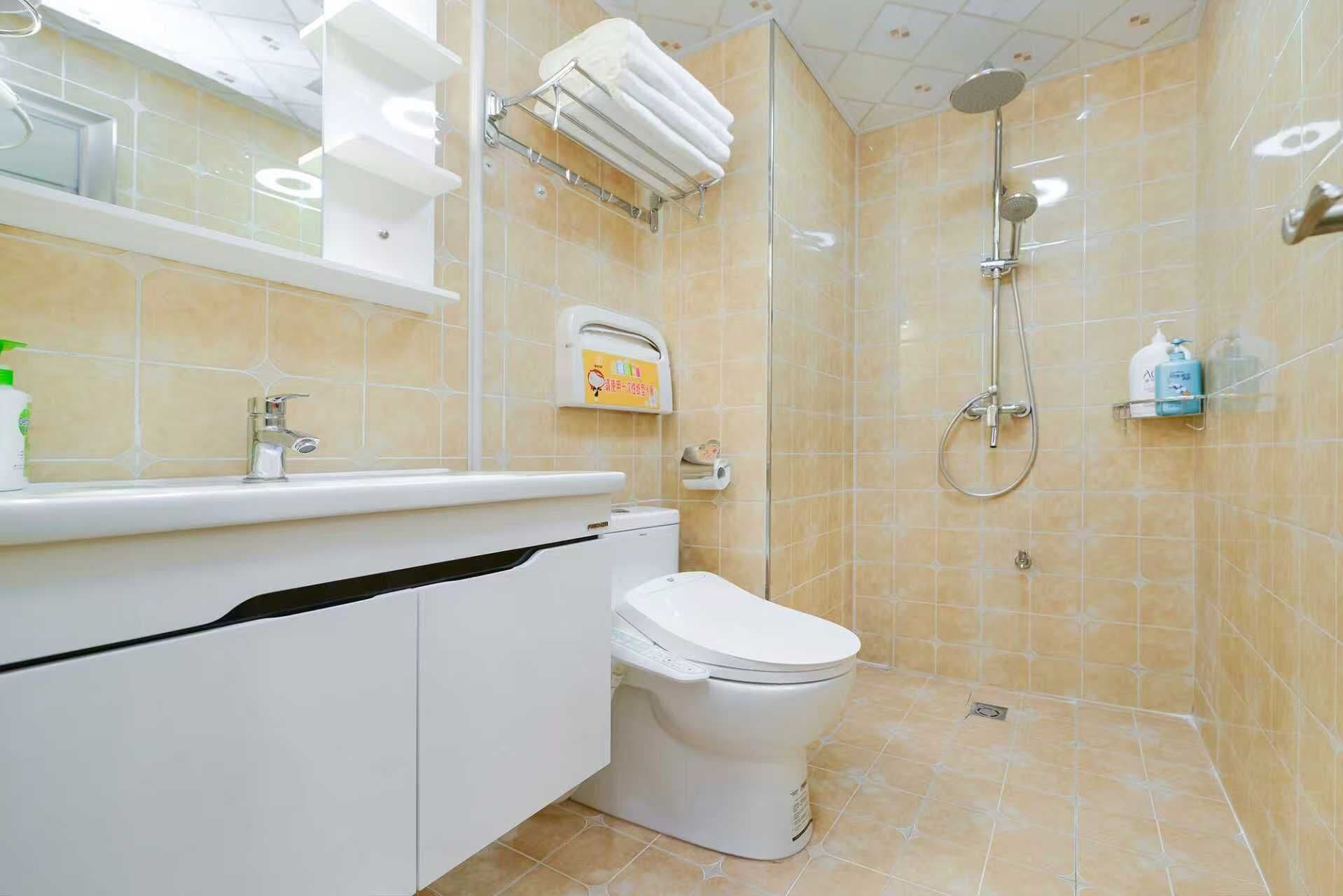 A bathroom with a toilet, sink, and shower. There are shelves with toiletries and a towel rack.