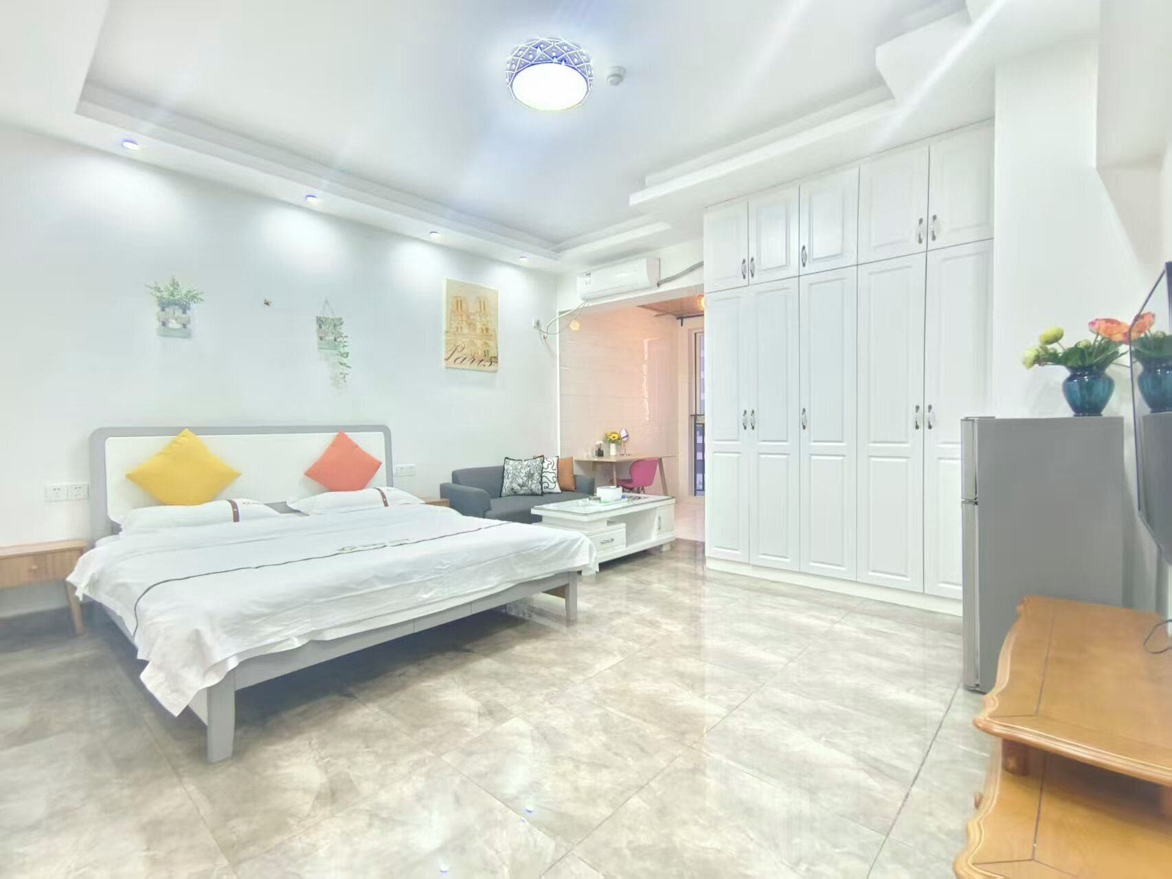 A modern bedroom with a bed, a desk, and a wardrobe.