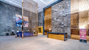 Eine geräumige Lobby mit Empfangsschalter, Sitzgelegenheiten und einem großen digitalen Bildschirm.