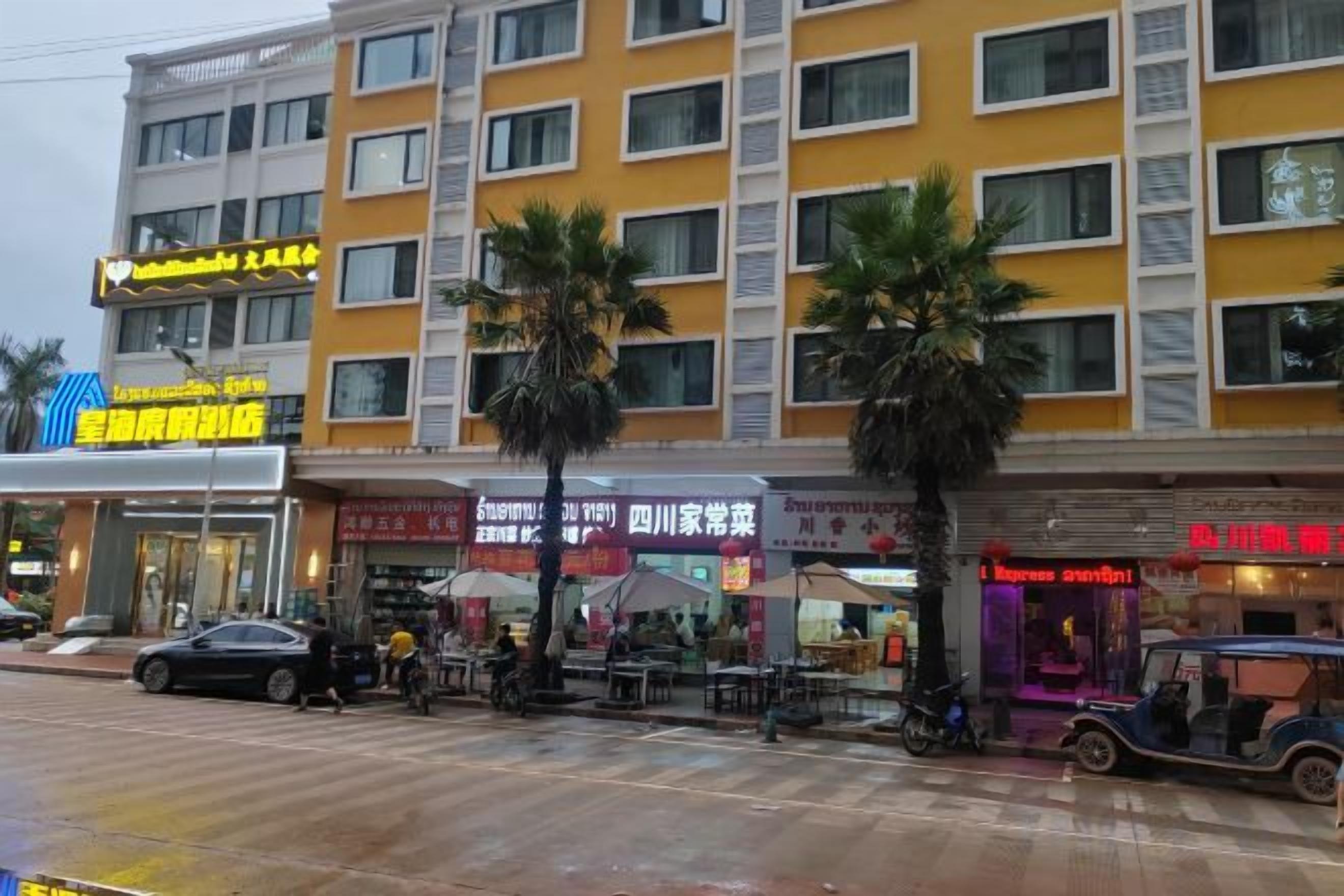 A multi-story building with commercial establishments on the ground floor, including a restaurant and a shop with a prominent sign.