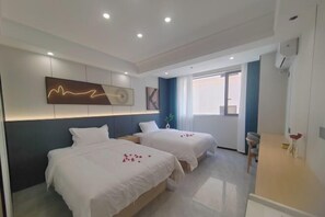 A hotel room with two beds, a modern light fixture, a window, and a desk. - XINGHAI HOTEL AND RESORT (Boten)