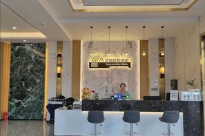 A hotel reception area with a marble wall, a reception desk, and bar stools. - XINGHAI HOTEL AND RESORT (Boten)