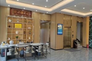 A hotel lobby with a reception desk, seating area, and an elevator. - XINGHAI HOTEL AND RESORT (Boten)