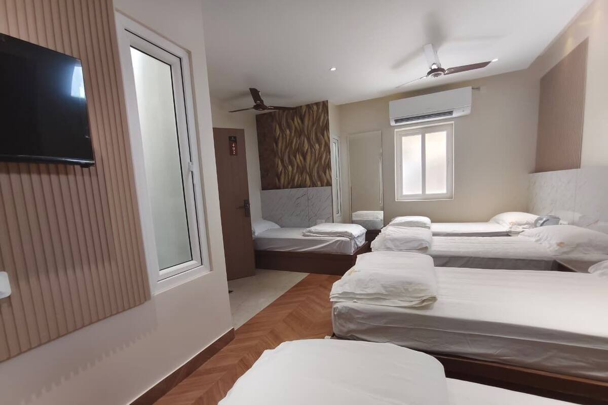 Ett hotellrum med tre sängar, en platt-TV, takfläktar och en luftkonditioneringsanläggning.