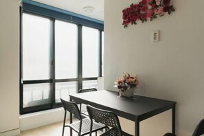 A room with a large window, a table with chairs, and a wall-mounted flower arrangement. - Seoul Full House/Hongdae Entrance Sta.Exit 7. Party room. Big House. Two Rooms. (Seoul)