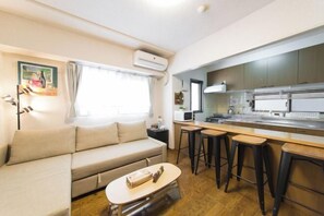 A compact living space with a sofa, a small table, a kitchenette, and a bar area. - Nestay apartment Tokyo Akihabara (Tokyo)