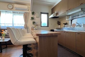 Una cocina moderna con barra, armarios de madera y un ventanal con cortinas.