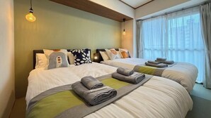 Ein Hotelzimmer mit zwei Betten, einer Holzbalkendecke und einem großen Fenster mit Vorhängen.