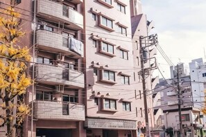 Un edifici residencial de diverses plantes amb balcons, una entrada ben visible i un cel clar.