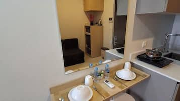 A compact hotel bathroom with a sink, mirror, and a small countertop with toiletries.
