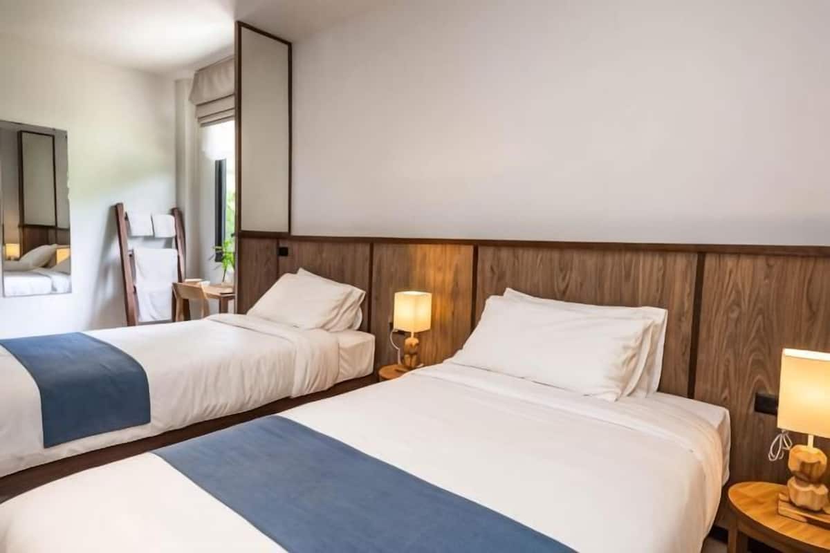 Ein Hotelzimmer mit zwei Betten, einem Holzkopfteil, Nachttischlampen und einem Spiegel.
